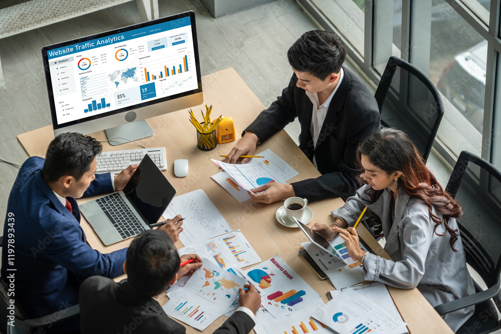 デスク上のグラフ資料とPC画面を見ながら市場調査を行う様子